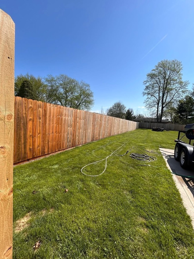 Freshly mowed lawn beside a cleaned wood privacy fence