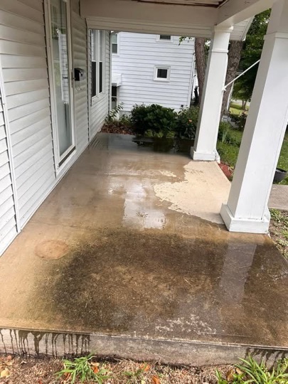 Concrete porch darkened by buildup before cleaning